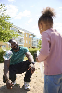 Father looking at daughter blowing bubbles