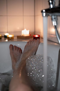 Female legs in bathtub with candles