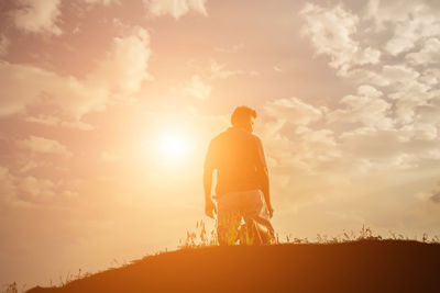 Rear view of man standing against sky during sunset