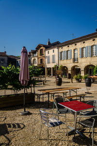 Empty chairs and tables against buildings in city