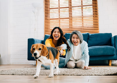 Portrait of young woman with dog sitting on sofa at home