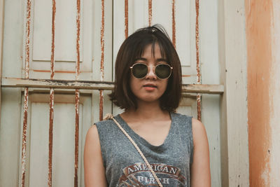 Portrait of young woman standing against wall