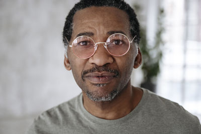 Mature man wearing pink glasses at home