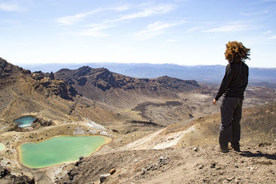 Male hiker with curly hair, looking at the view of the emerald lakes