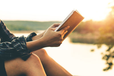 Midsection of man using mobile phone against sky