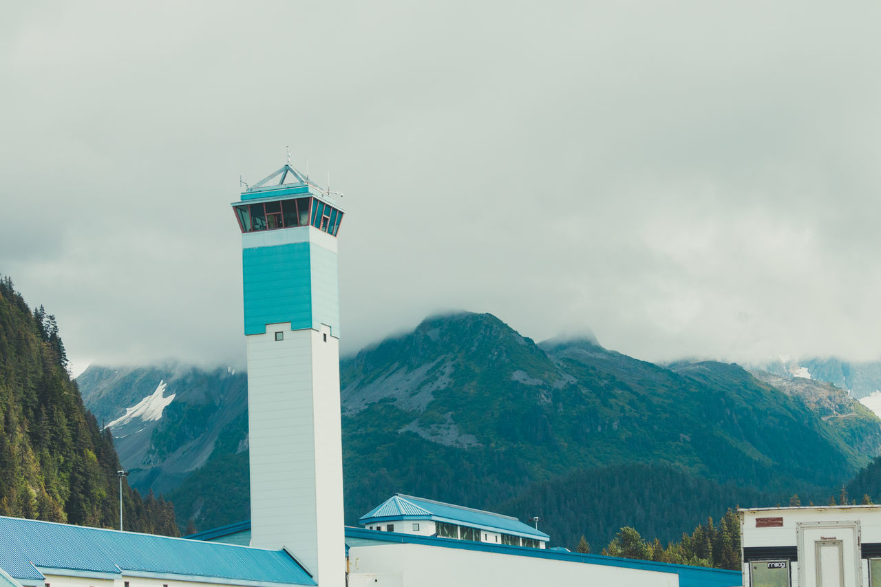 LIGHTHOUSE BY BUILDINGS AGAINST SKY