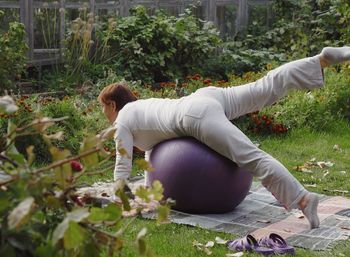 An elderly woman practices yoga in the fresh air.