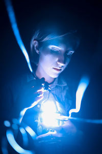 Close-up of woman holding illuminated light in the dark