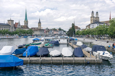 Boats at dock in river limmat of zurich. historic city, fraumünster church and grossmunster church.