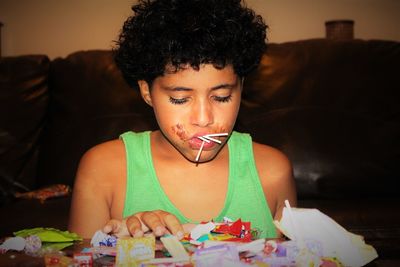 Boy with curly hair eating candies at home