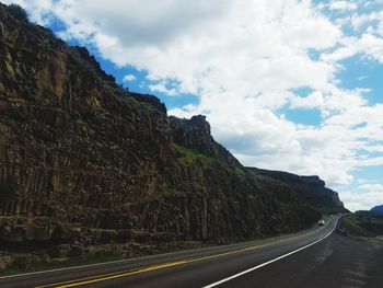 Road by mountain against sky