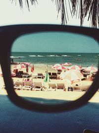 Deck chairs and parasols at beach seen through sunglasses