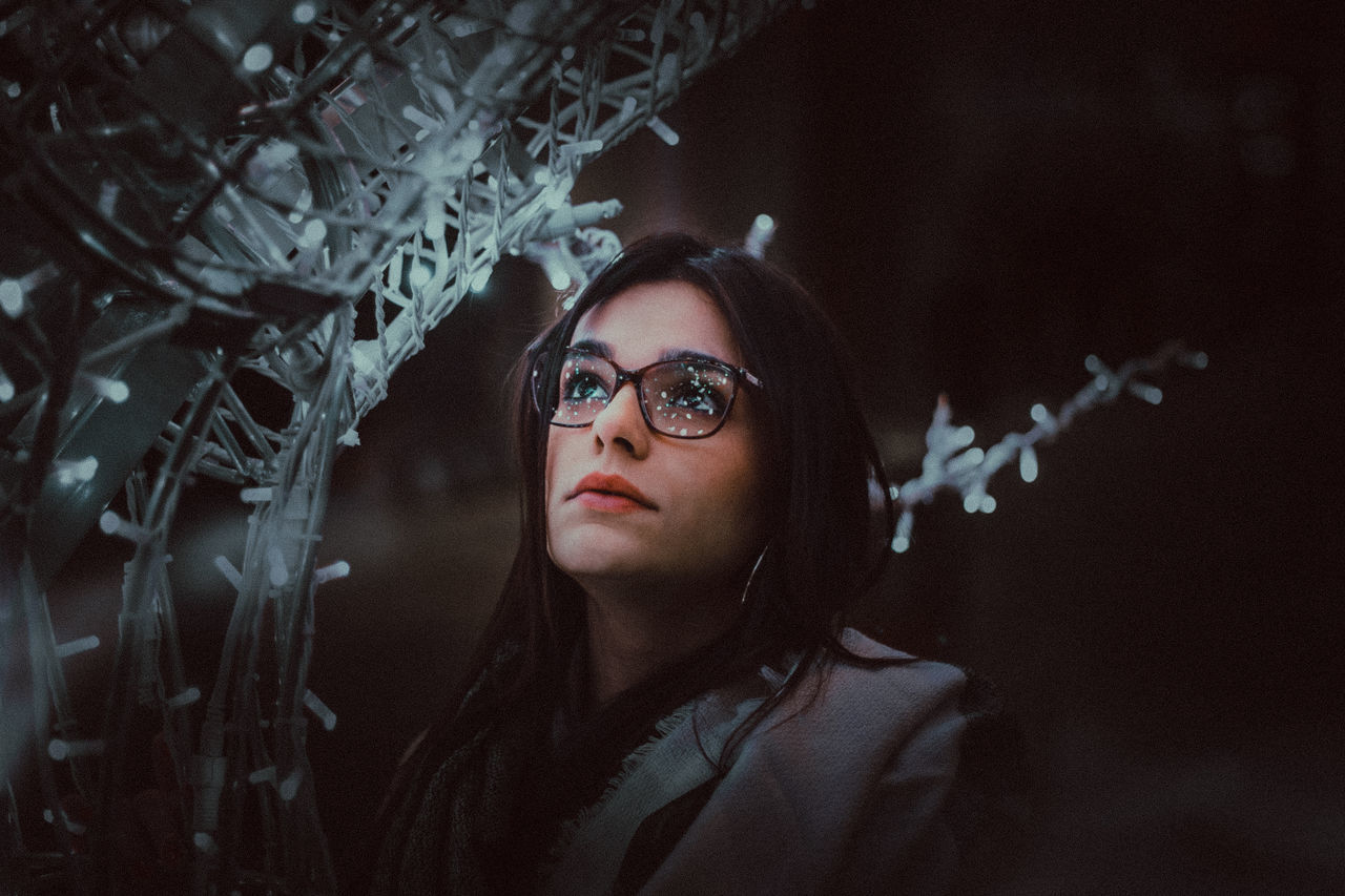 Close-up of woman by string lights