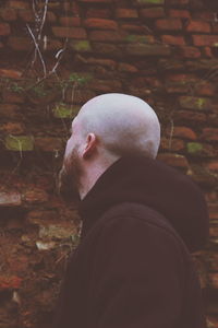 Rear view of man standing against brick wall