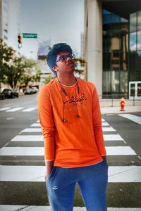 Young man wearing sunglasses standing on road in city