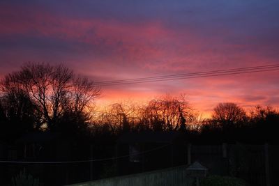 Silhouette trees against dramatic sky during sunset