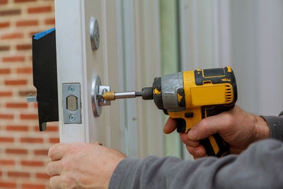 Cropped hand using nail gun on door at home