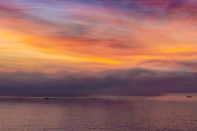 Scenic view of sea against dramatic sky during sunset