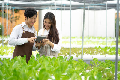 Young woman using mobile phone while standing in greenhouse