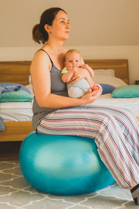 Young woman sitting on bed at home