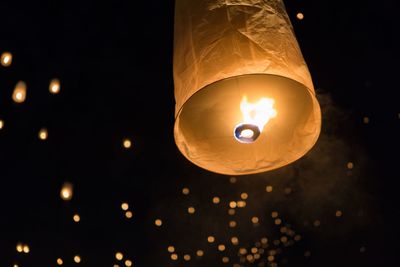 Low angle view of illuminated lighting equipment against black background