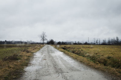 Road amidst field against sky