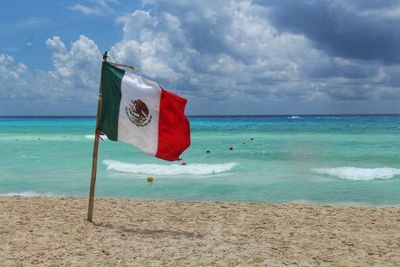 Scenic view of flag on beach against sky