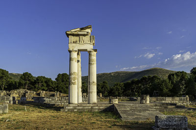 Columns of ancient greek temple on field against sky in epidauros