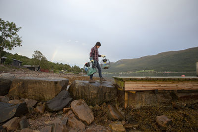 A norwegian man carrying crab pots near the fjord