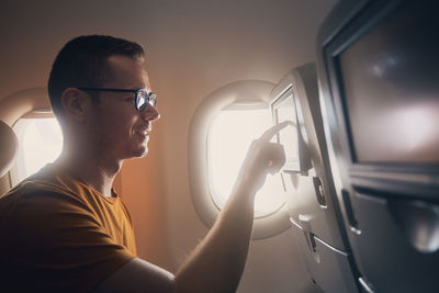 Happy man travel by airplane. passenger using inflight entertainment system and internet connection.