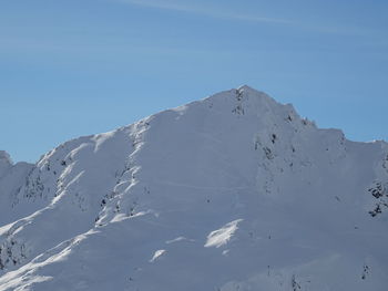 Low angle view of snowcapped mountain against clear blue sky