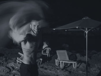 Blurred motion of happy man standing on sand at beach