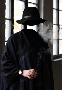 Digital composite of invisible woman holding cigarette