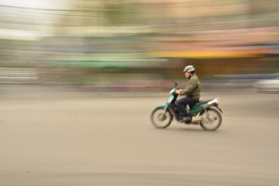 Blurred motion of man riding motorcycle on road