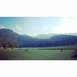 People on grassy field against sky