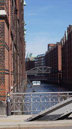 Bridge over river amidst buildings in city against sky