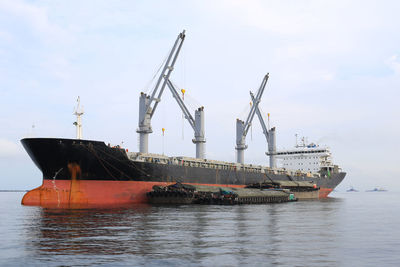 Cranes at commercial dock against sky