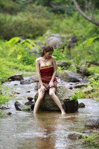 Man in front of woman in river stream in forest