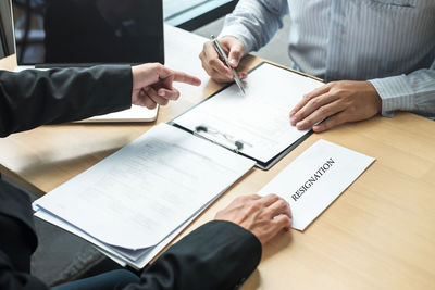 Low section of man holding paper with text on table