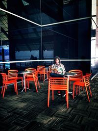 Man reading book while sitting on chair at sidewalk cafe