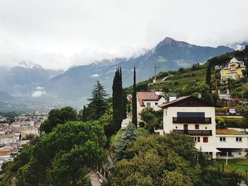 Trees and townscape against sky, merano, italy