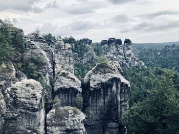 View of rocks on landscape against cloudy sky