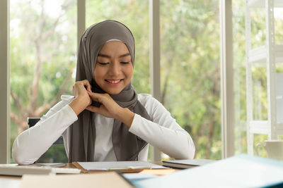 Portrait of smiling young woman sitting on table