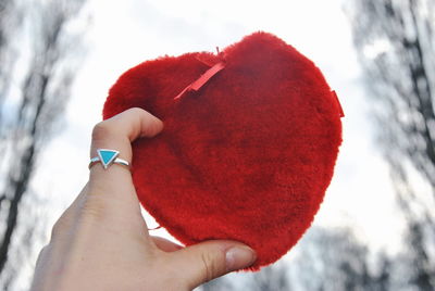 Close-up of woman holding red heart shape in winter