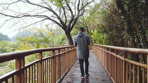 Rear view of man walking on footbridge