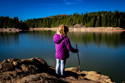 Girl standing on rock by lake during winter