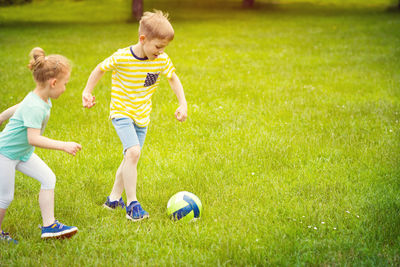 Full length of kids playing football on grass