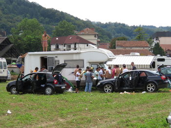 People on field by houses against buildings