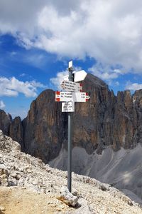 Sign on rock by road against sky