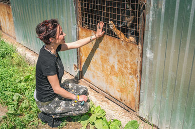 Dog at the shelter.  lonely dogs in cage with cheerful woman volunteer